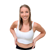 Smiling woman in a white athletic tank top, standing with hands on hips, isolated on a white background.
