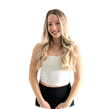 Young woman with long blonde hair, wearing a white sleeveless top and black pants, smiling at the camera.